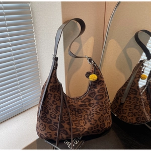 Detail view of leopard print hobo bag with suede texture and yellow pompom charm