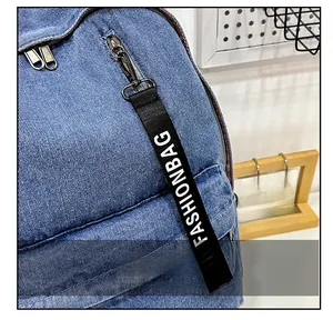 Detail of blue denim backpack showing fashion strap and metal zipper on textured fabric