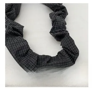 Close-up of black and white checkered scrunchie shoulder strap with elastic pleats