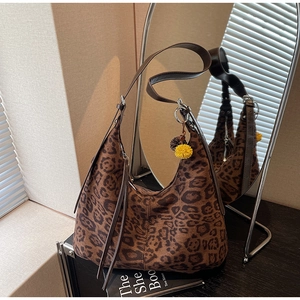 Close-up of leopard print hobo bag with brown leather strap and decorative pompom