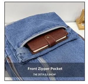 Detail of the front zipper pocket on a blue denim backpack with a brown wallet inside