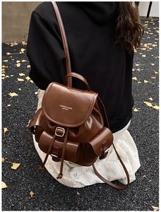 Detail of dark brown vintage backpack featuring utility pockets and metallic buckles