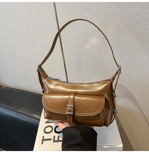 Close-up of brown leather hobo bag featuring metallic buckles and side ring details