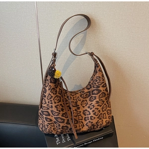 Detail of hobo leopard print tote bag with plush pompom charm and leather strap