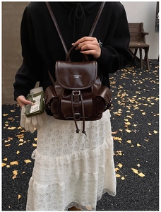 Outdoor shot of a vintage brown leather backpack among autumn ginkgo leaves