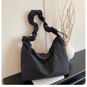 Detail of checkered canvas hobo bag featuring a unique ruffled scrunchie shoulder strap