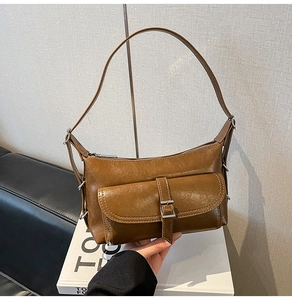 Detail of vintage brown shoulder bag with oiled leather texture and metal buckle pocket