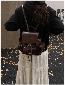 Detail of dark brown leather backpack with drawstring closure and silver buckles
