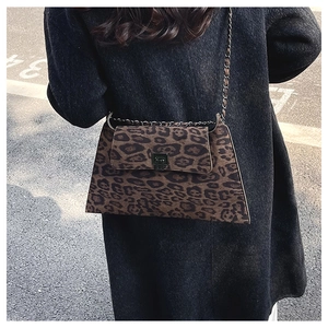 Detail of leopard print crossbody bag with metal chain strap and twist lock on a wool coat