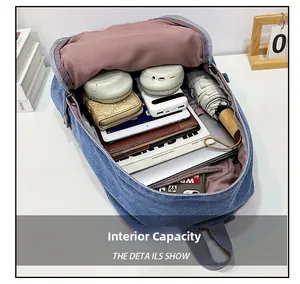 Spacious interior of blue denim backpack showing multi-layer pockets and pink lining