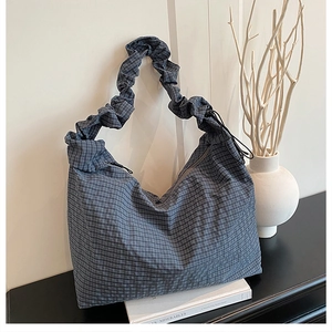 Detail of blue checkered tote bag with scrunchie style strap and drawstring side feature