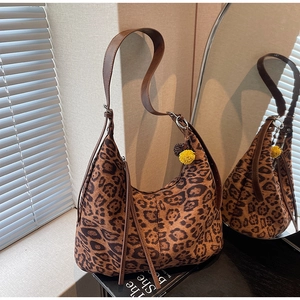Detail of leopard print hobo bag with brown strap and yellow charm on a magazine