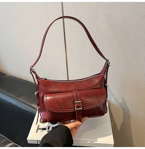 Detail of burgundy leather shoulder bag with silver buckle and grainy texture finish