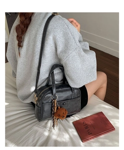 Detail of black PU leather pillow bag with bear charm and scarf accessory on a model