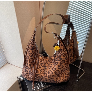 Detail view of leopard print hobo bag with leather strap and decorative yellow pompom