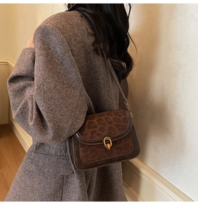 Borsa a tracolla retrò con patta leopardata marrone e fibbie dorate indossata su un cappotto