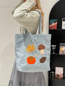Sac fourre-tout en velours côtelé bleu clair avec broderie porté par un mannequin