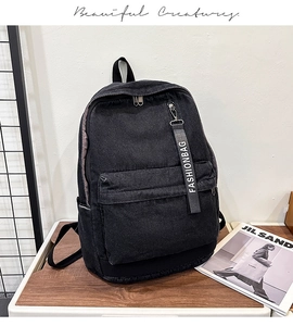 Close-up of black denim backpack with a square front pocket and a fashion logo strap
