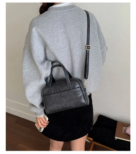 Detailed view of black matte leather crossbody bag with adjustable strap and gold buckles