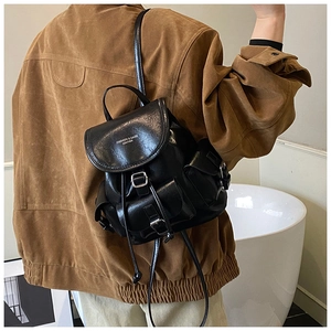 Detail of black faux leather mini backpack featuring silver buckles and multiple pockets