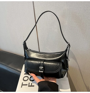Detail of glossy black shoulder bag with silver buckle and metallic zipper closure