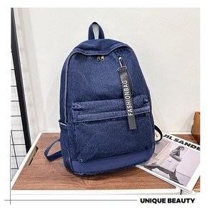 Detailed texture of dark blue denim backpack featuring stylish fashionbag ribbon charm
