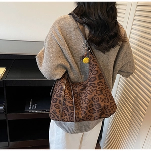 Detail of leopard print tote bag with brown shoulder strap and fuzzy pompom accessory