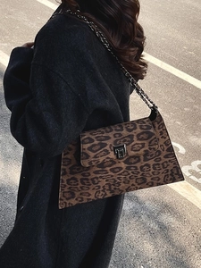 Retro leopard print crossbody bag with metal chain strap worn by a model in the street