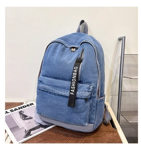 Detailed shot of large blue denim backpack featuring a front pocket with fashionbag zipper strap