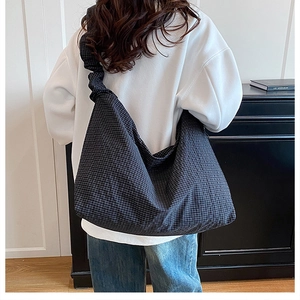 Detail of grid pattern canvas hobo bag showing large capacity and soft fabric drape on shoulder