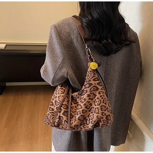 Detailed back view of a large leopard print hobo bag with brown leather strap and pompom