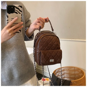 Détail du mini sac à dos matelassé marron foncé avec chaîne et poche à fermoir