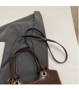 Vue détaillée du sac à main marron avec bandoulière réglable sur une veste de costume