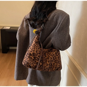 Detailed side view of leopard print hobo bag with plush charms on a model shoulder