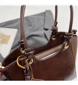 Détail du cabas en cuir marron foncé avec boucles dorées et poignée nouée