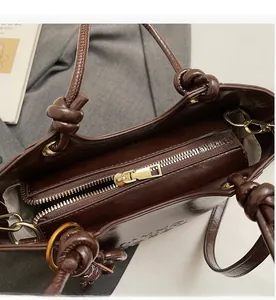 Détail de la fermeture éclair dorée et du cuir brillant marron foncé du sac seau