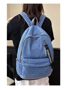 Detail of light blue denim backpack showing texture, front pocket, and fashion strap
