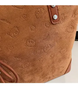 Close-up of brown suede tote bag with embossed bear patterns and metal rivets