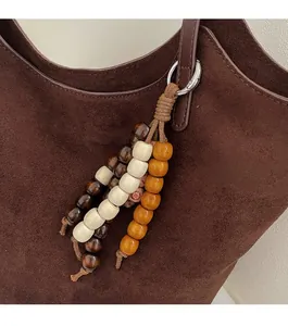 Détail d'un pendentif en perles de bois bohème crème et orange sur un sac brun