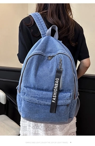 Detailed close-up of blue denim backpack showing fashionbag strap and front zipper pocket