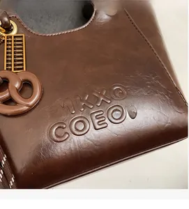 Gros plan du lettrage embossé sur sac seau en cuir marron avec détails dorés