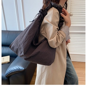 Detail of ruffled shoulder strap on large dark checkered canvas tote bag for women