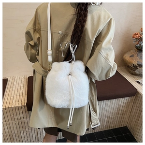 Detailansicht einer weißen Plüsch-Beuteltasche mit Lederriemen an einem Trenchcoat