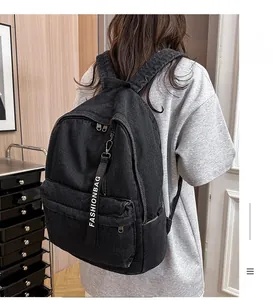 Rear view of black denim backpack with fashion ribbon strap on a person's back