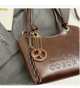 Détail d'un sac seau marron foncé avec logo embossé et texture en similicuir grainé