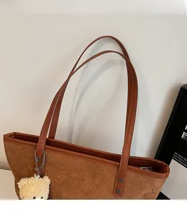 Detail of brown suede tote bag featuring embossed bear patterns and comfortable shoulder strap