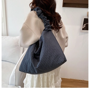 Detail of blue plaid canvas tote bag with pleated shoulder strap on model back view