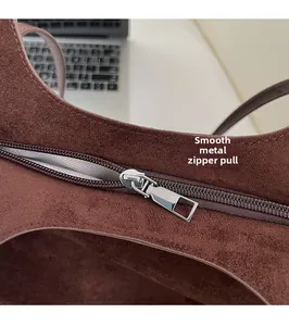 Vue détaillée de la fermeture éclair fluide et de la doublure à chevrons du sac en daim marron