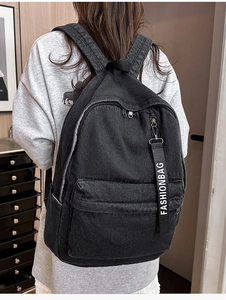 Detail view of black denim backpack with fashionbag ribbon on front zipper pocket