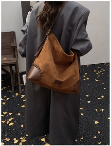 Detail of suede hobo bag with leather stitching and woven seams on autumn coat